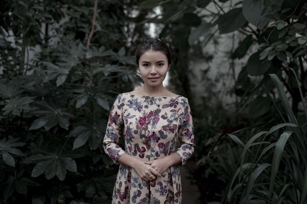 Asian woman smiling near foliage