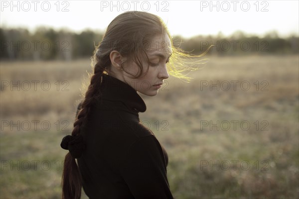 Pensive Caucasian woman standing in field