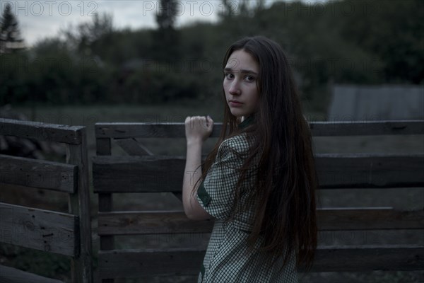 Caucasian woman leaning on wooden gate