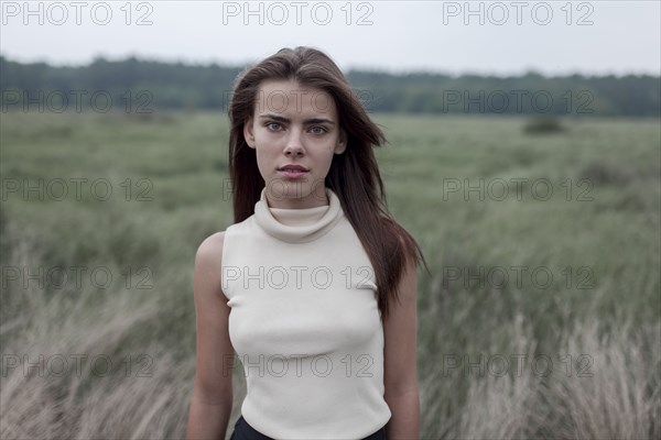 Serious Caucasian teenage girl standing in field