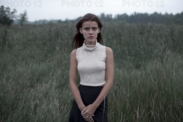 Serious Caucasian teenage girl standing in field