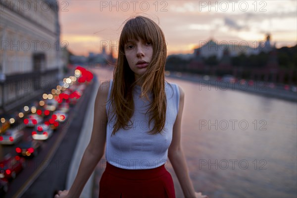 Serious Caucasian woman standing at urban waterfront