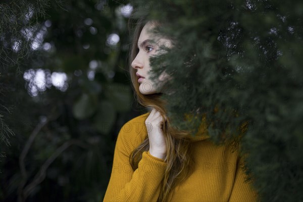 Pensive Caucasian woman standing near tree branch