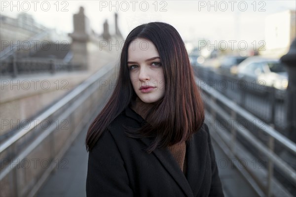 Serious Caucasian girl standing on footbridge