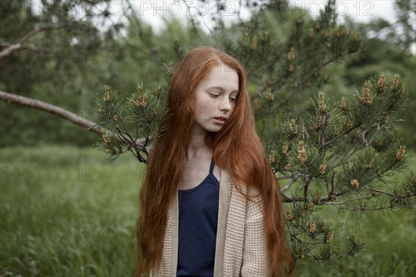 Caucasian girl standing near tree branch