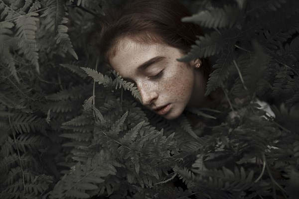 Caucasian girl with freckles resting in leaves