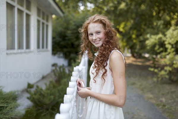 Smiling Caucasian girl standing near fence