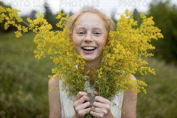 Portrait of smiling Caucasian girl with freckles holding wildflowers