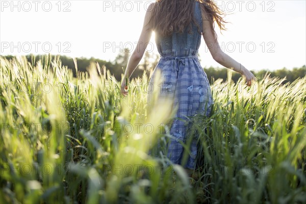 Caucasian woman walking in field of tall grass