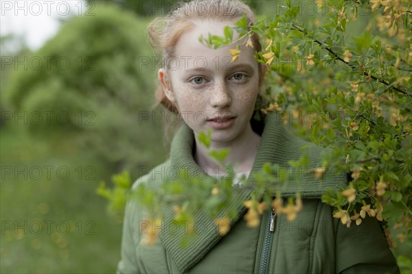 Close up of Caucasian girl standing near branch