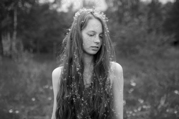 Caucasian girl standing in field with fuzz in hair