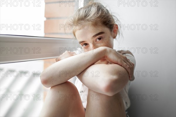 Caucasian girl sitting on windowsill