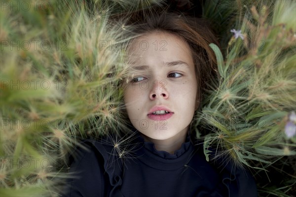 Concerned Caucasian girl laying in field