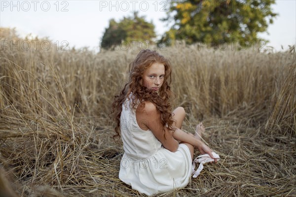 Caucasian girl sitting in wheat
