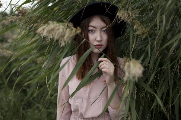 Asian woman standing in foliage