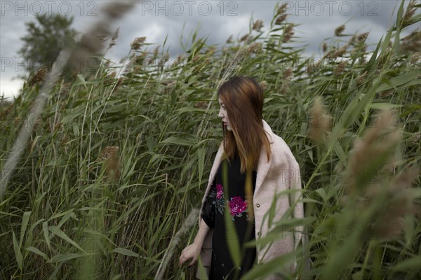 Asian woman standing in field of tall grass