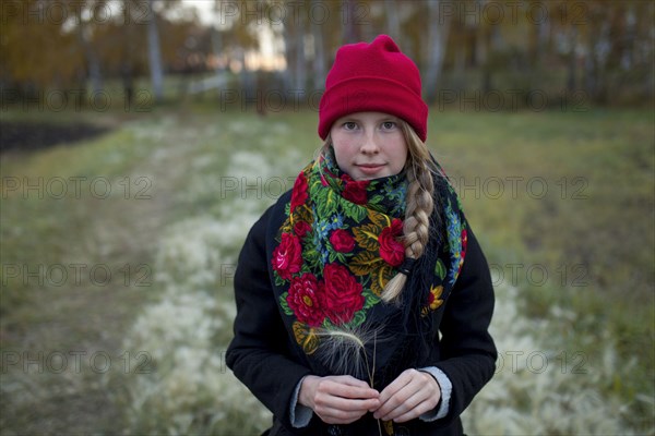 Portrait of Caucasian woman wearing scarf and stocking-cap holding hay seed