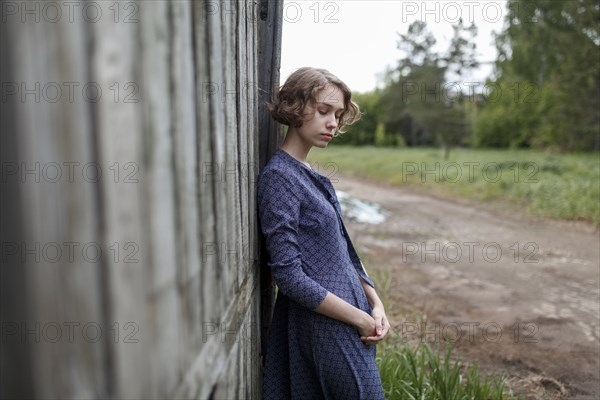 Pensive Caucasian woman leaning on wooden fence