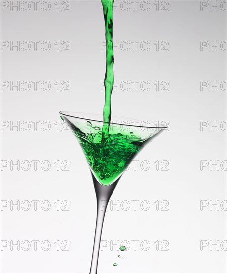 Green liquid filling martini glass