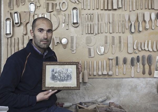 Carpenter holding old photograph in workshop