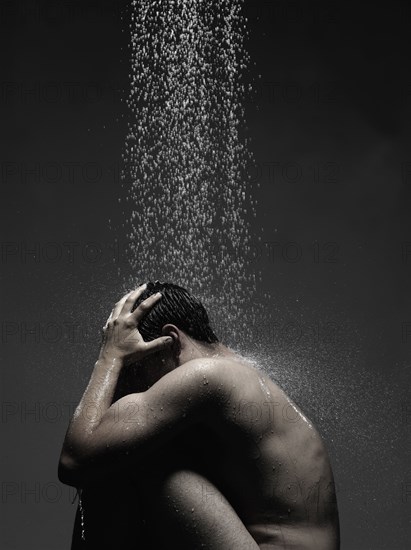 Caucasian man sitting in shower