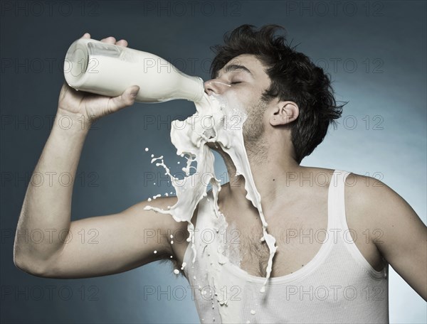 Caucasian man drinking milk and spilling it