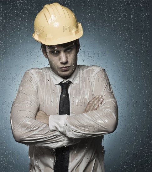 Caucasian businessman in hard-hat standing in rain