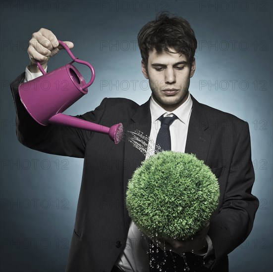 Caucasian businessman watering plant