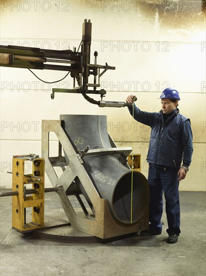 Caucasian worker working on steel pipe in factory