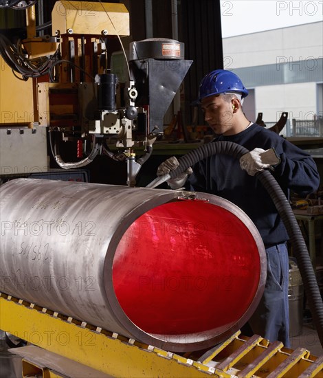 Caucasian worker working on steel pipe in factory