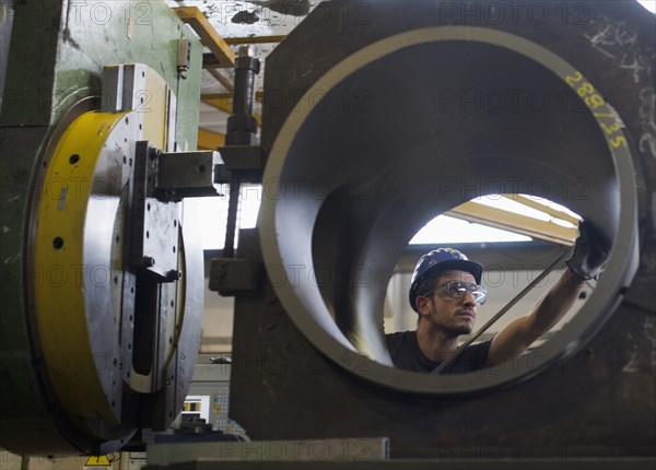 Caucasian worker working on steel pipe in factory