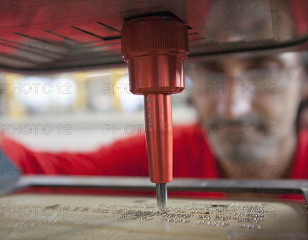 Caucasian worker using branding machine in factory