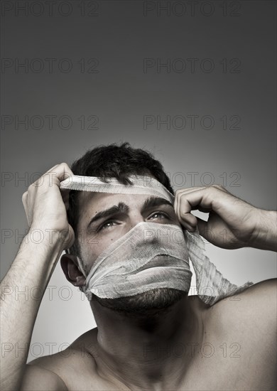Man removing bandage from his face