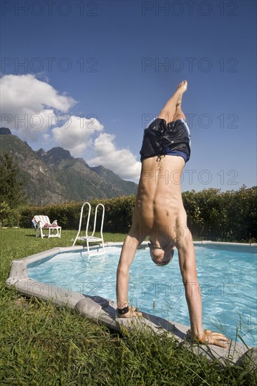 Man doing handstand on edge of swimming pool