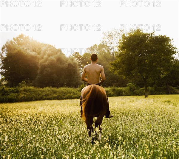 Caucasian man riding horse in field