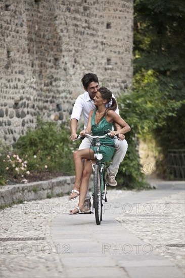 Caucasian couple riding bicycle together