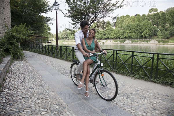 Caucasian couple riding bicycle together