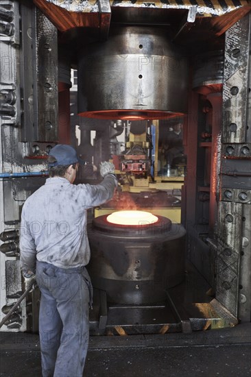 Caucasian worker operating steel melting machinery in factory
