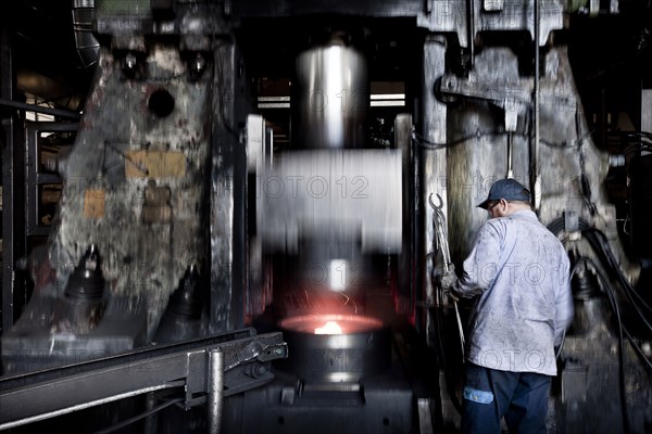 Caucasian worker operating steel melting machinery in factory