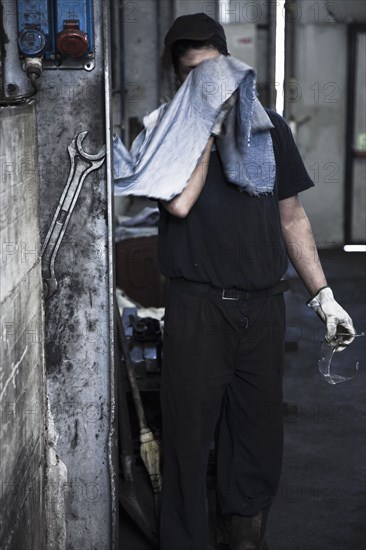 Caucasian worker wiping his face in factory