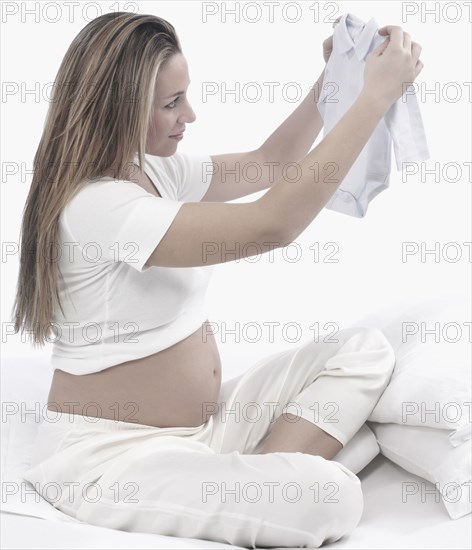 Pregnant Caucasian woman folding baby clothes