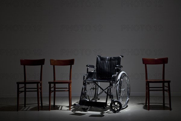 Wheelchair in line of wooden chairs