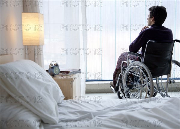 Pensive Caucasian man in wheelchair by window