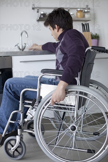 Caucasian man in wheelchair using kitchen sink