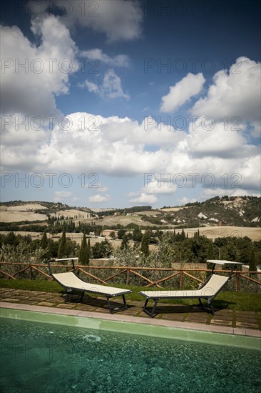 Lawn chairs by pool in rural landscape