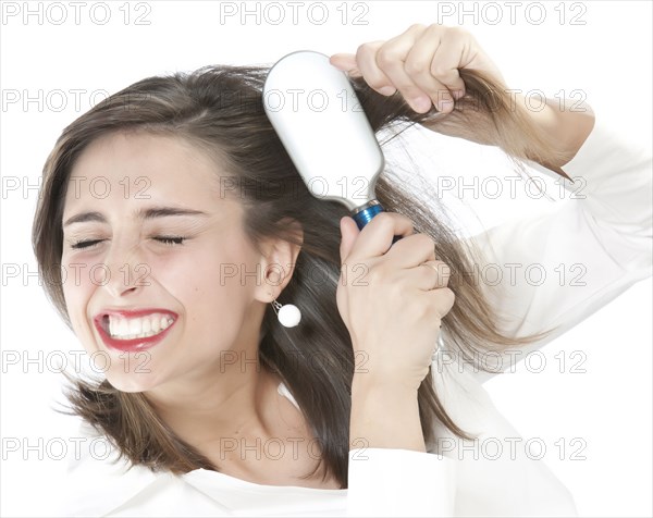 Grimacing woman brushing tangles from hair