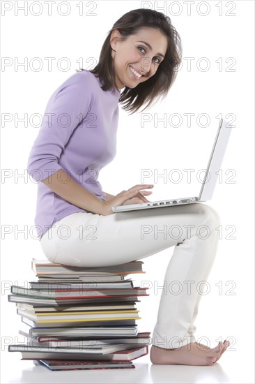 Woman using laptop on stack of books