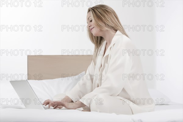 Caucasian woman using laptop on bed
