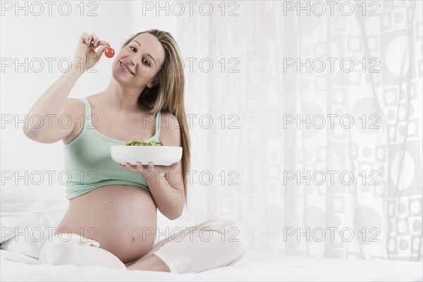 Pregnant Caucasian woman eating salad