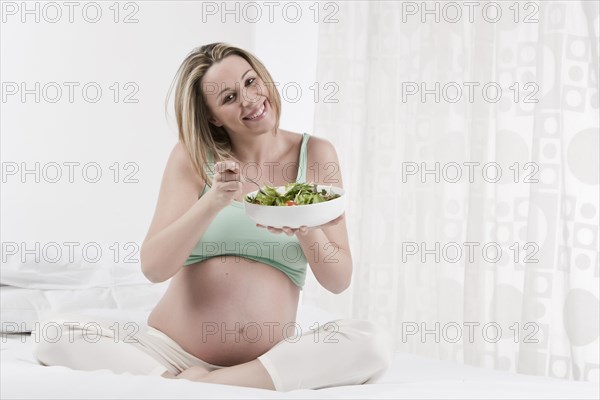 Pregnant Caucasian woman eating salad